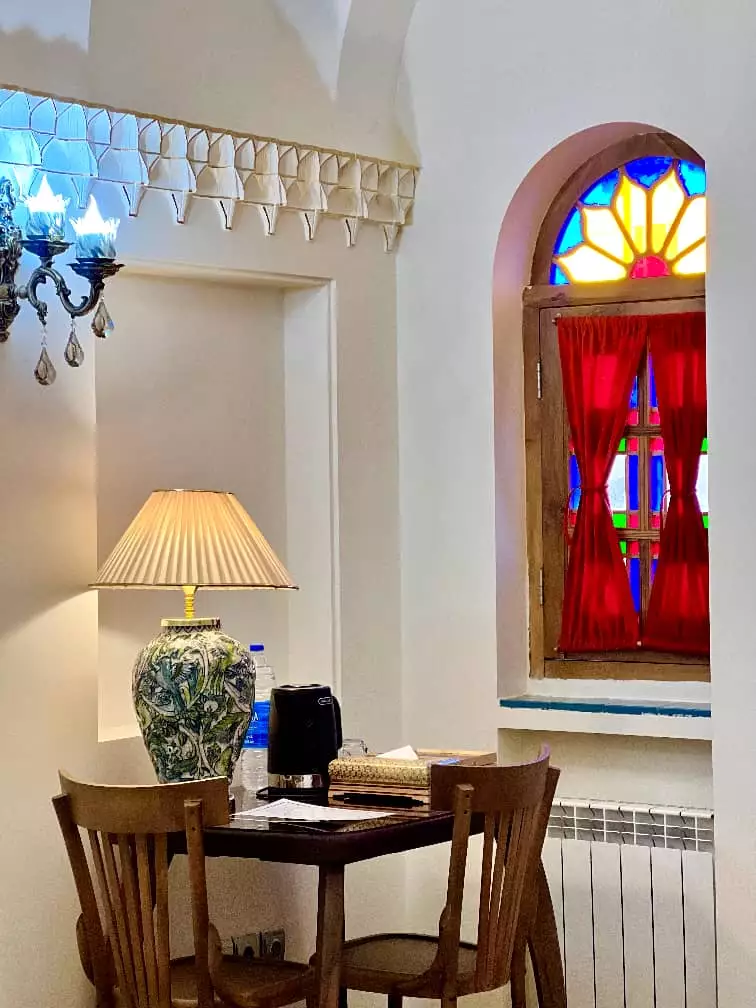 میز و صندلی کنار پنجره رنگی عمارت سهروردی