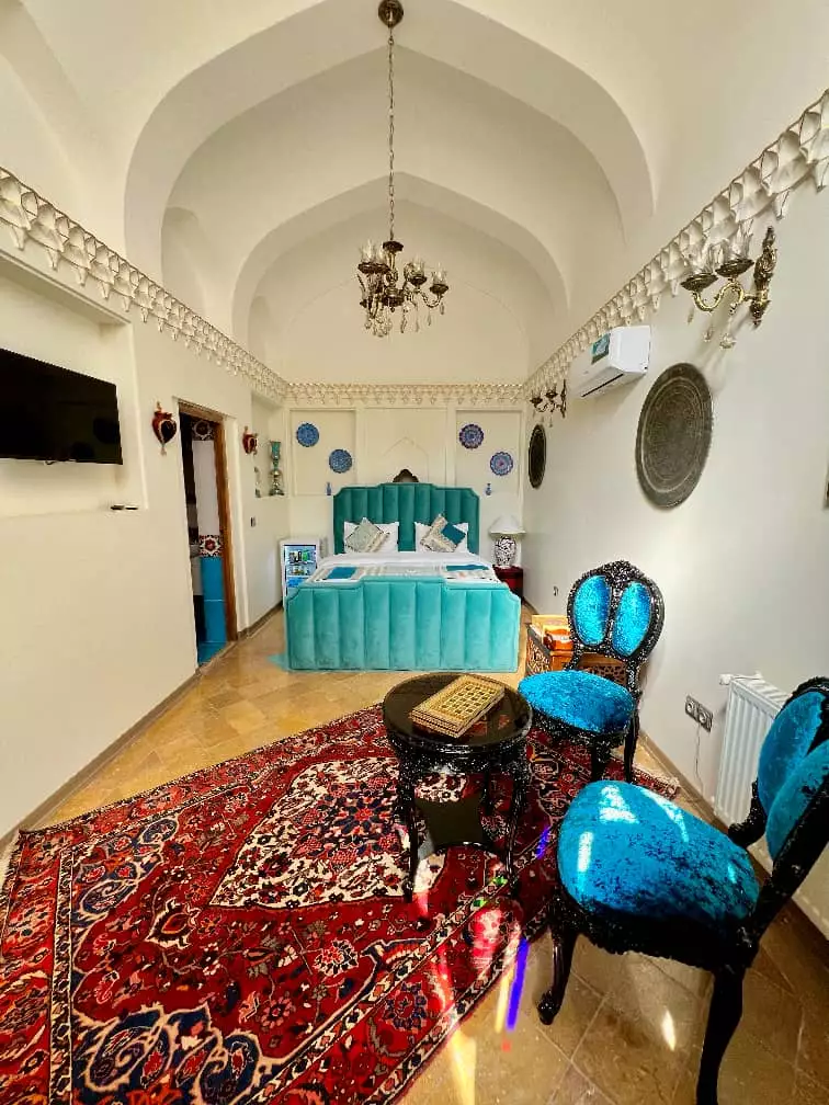 اتاق عمارت سهروردی با تخت فیروزه‌ای و فرش دستباف
