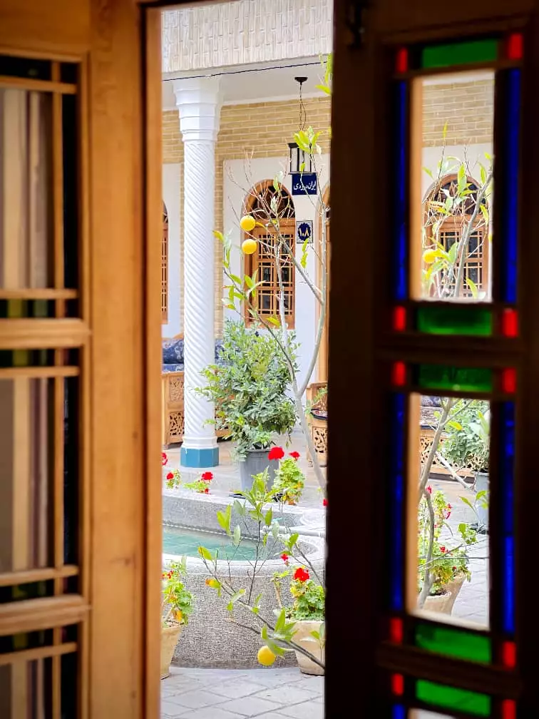 حیاط گل‌کاری‌شده عمارت سهروردی از پشت در رنگی