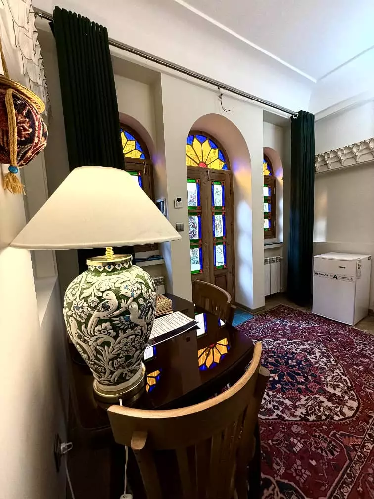 میز چوبی کنار پنجره‌های رنگی عمارت سهروردی