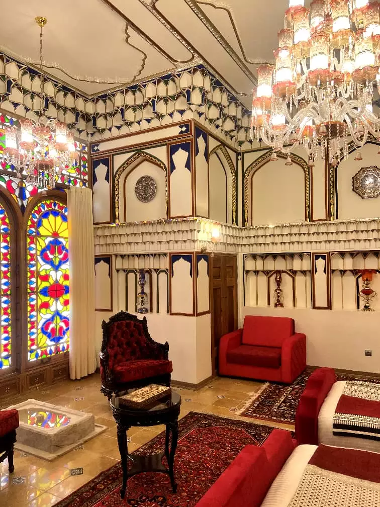 نشیمن عمارت سهروردی با پنجره‌های رنگی و مبل‌های قرمز