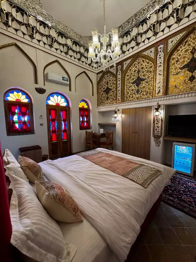 اتاق خواب عمارت سهروردی با تخت و پنجره‌های رنگی