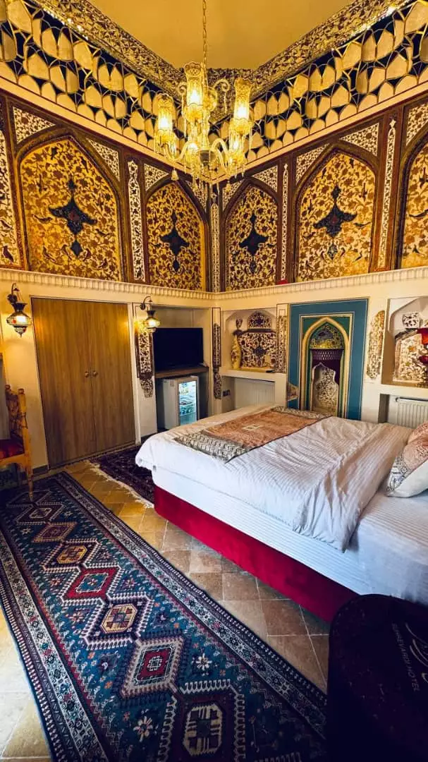 اتاق خواب عمارت سهروردی با تخت و دیوارنگاره‌های طلایی