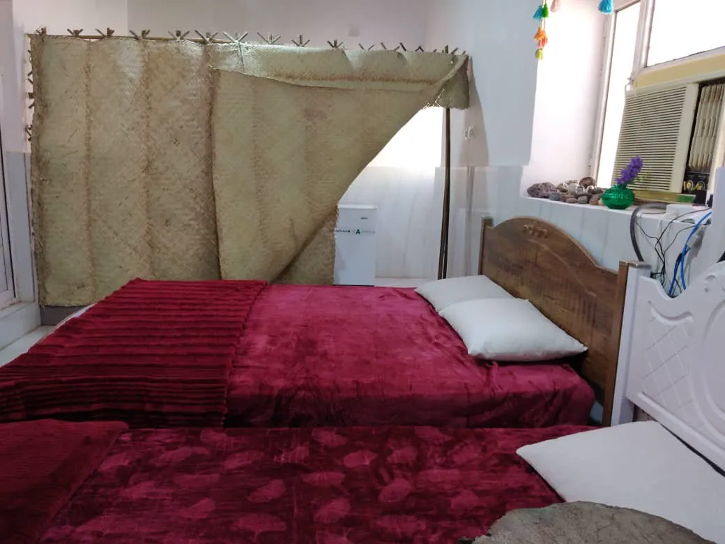 دو تخت با روتختی زرشکی در اتاق دنج