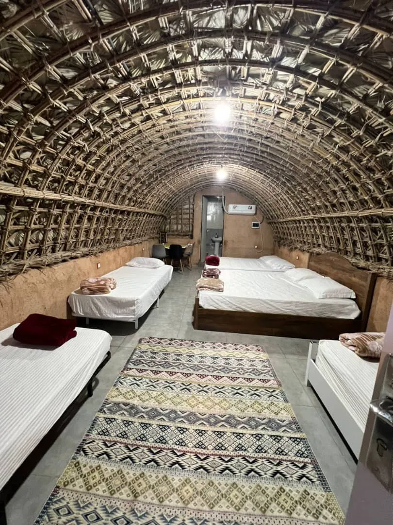 اتاق خوابگاه دنج با تخت‌های متعدد و سقف حصیری