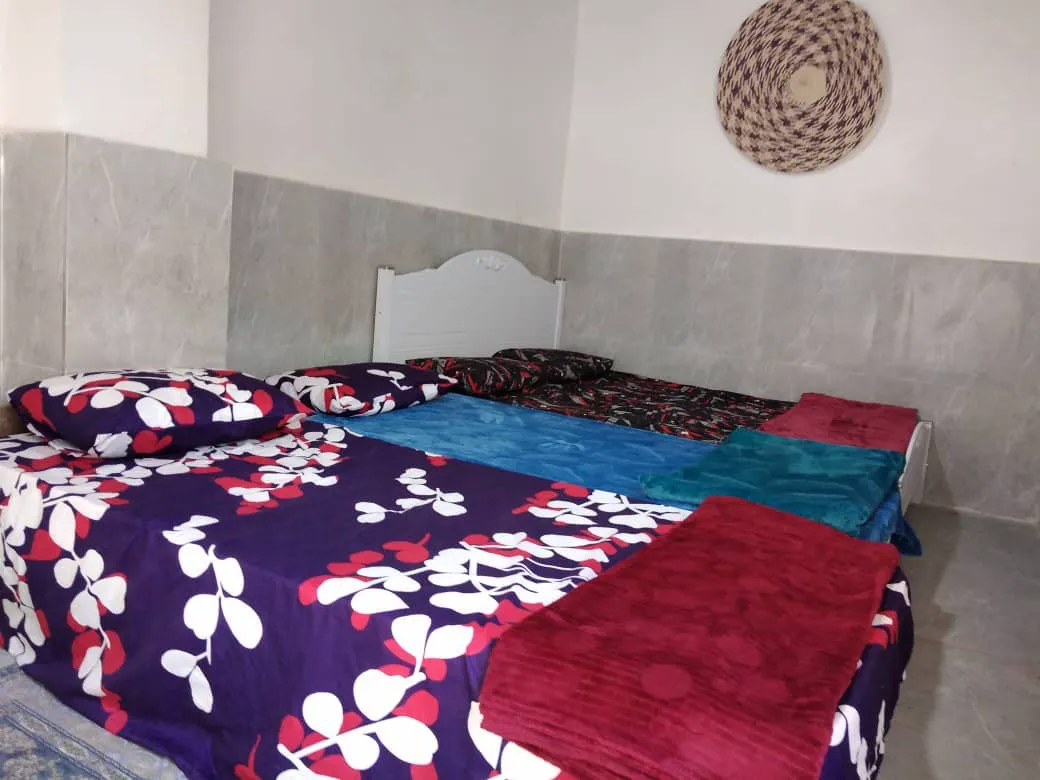 تخت دونفره با روتختی گل‌دار در اقامتگاه دنج
