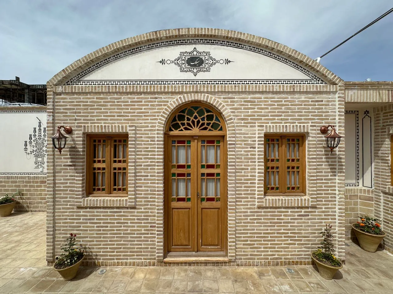 نمای آجری ورودی عمارت ایرانی با در چوبی قوسی