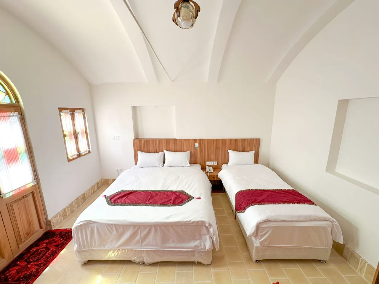 اتاق عمارت ایرانی با یک تخت دونفره و یک تخت یک‌نفره