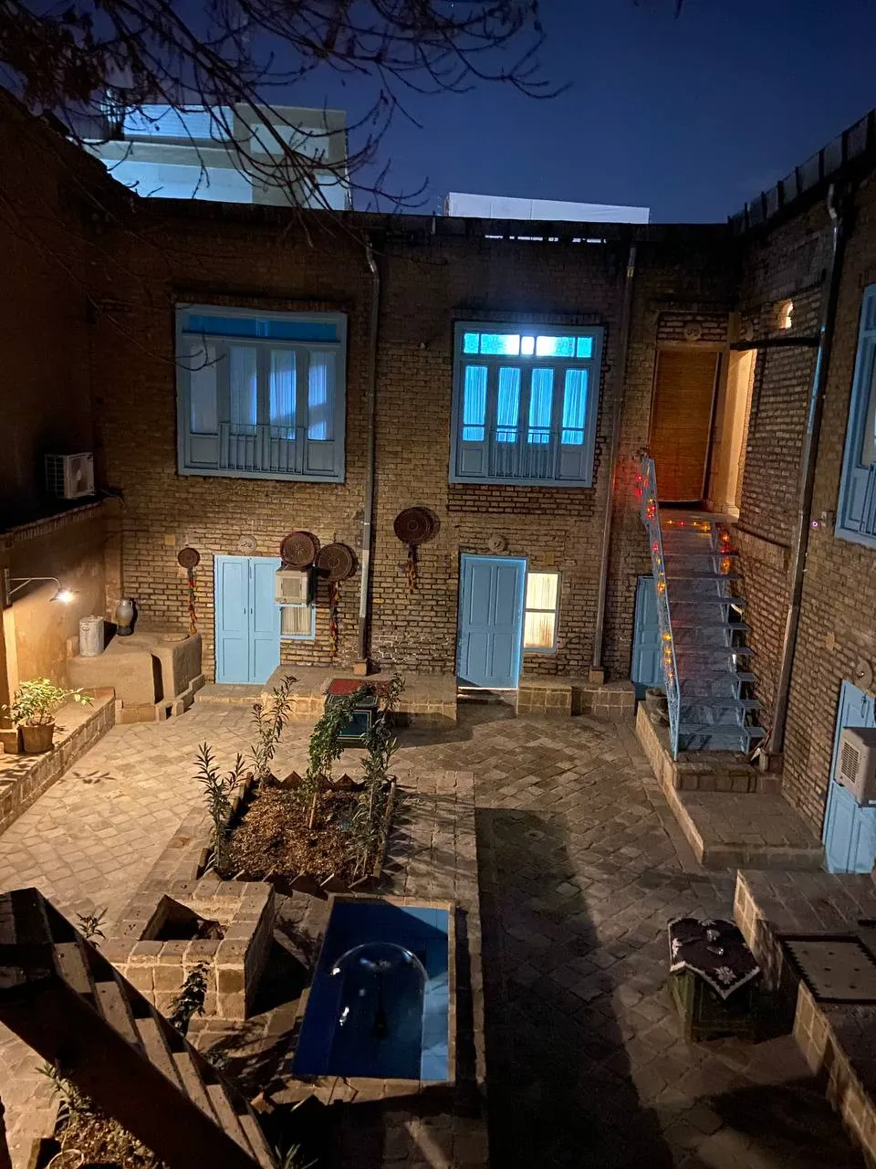 حیاط اقامتگاه آشتی کنان در شب با نور پنجره‌ها