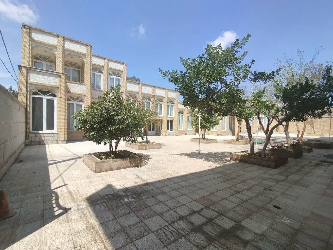 حیاط سنگفرششده هتل نصر کارمانیا با درختان