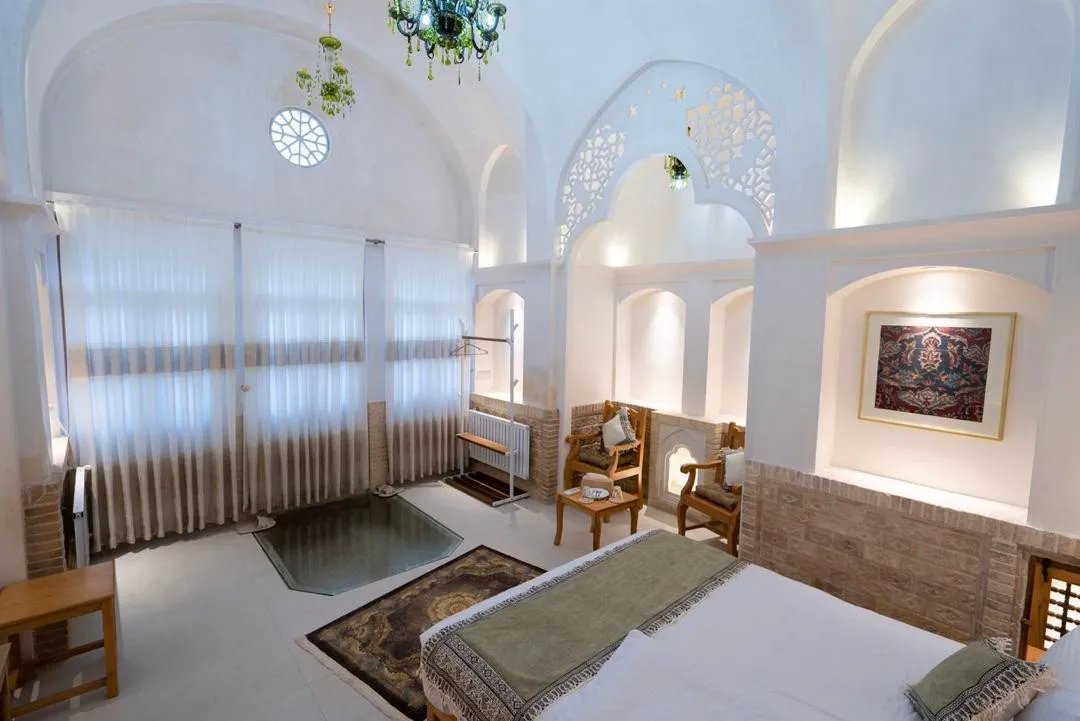 اتاق روشن با طاق‌های گچ‌بری و تخت هتل رزاس