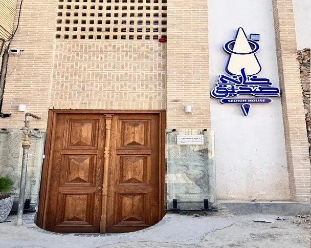 ورودی چوبی خانه صدیق با تابلوی هتل
