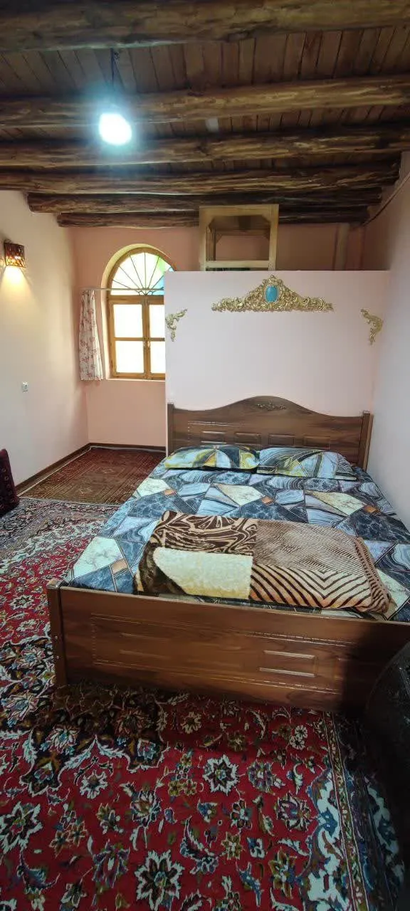 تخت چوبی و فرش قرمز در اتاق شادمهر