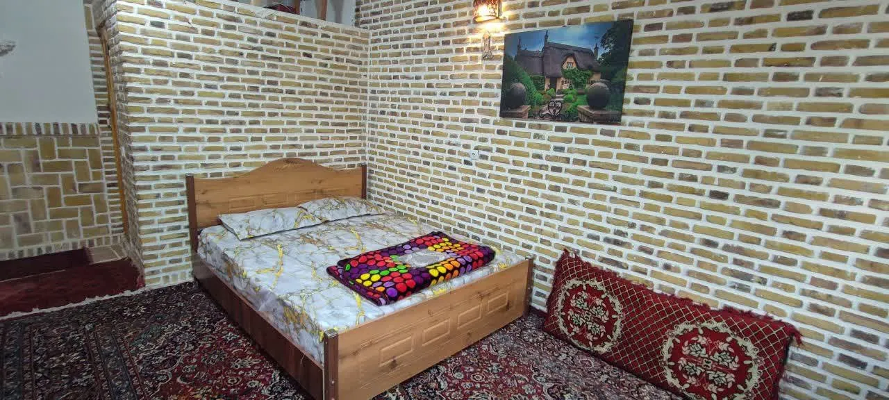 تخت چوبی و رختخواب رنگی در اتاق شادمهر