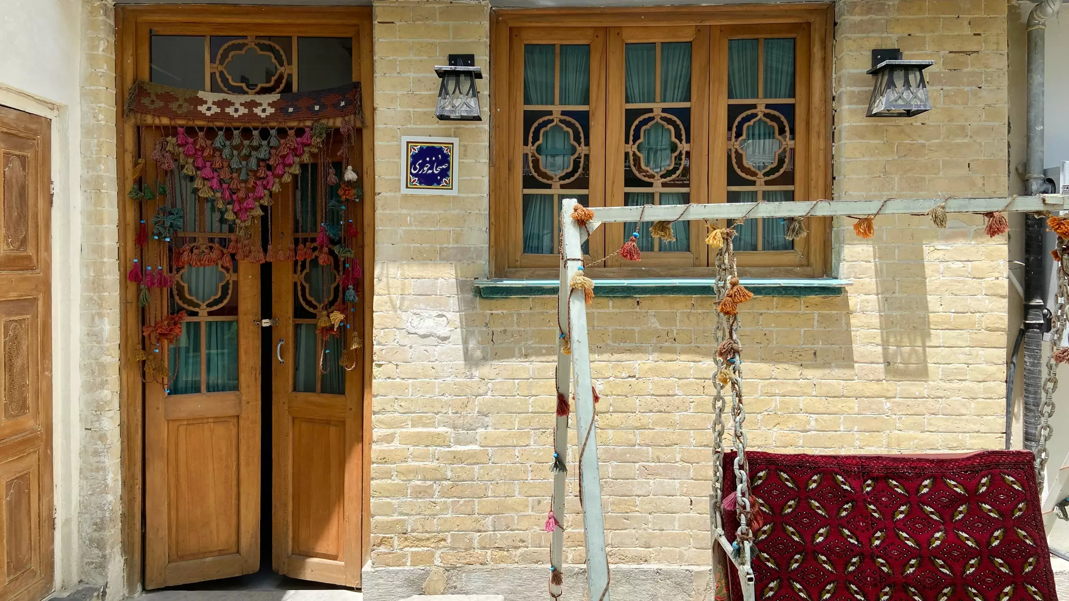 نمای آجری هتل سلطانی با در چوبی و تاب سنتی