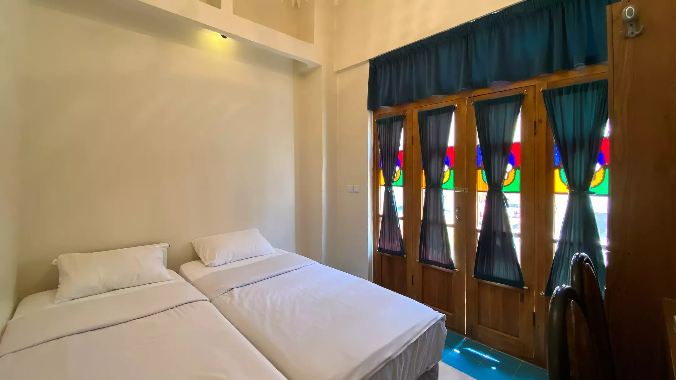دو تخت یک‌نفره کنار پنجره رنگی هتل سلطانی