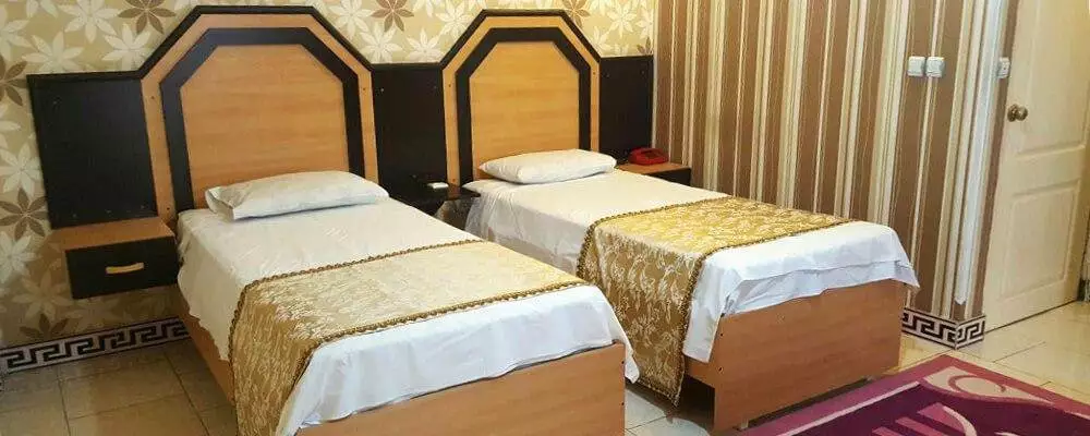 دو تخت یک‌نفره با روتختی طلایی در هتل بهمن