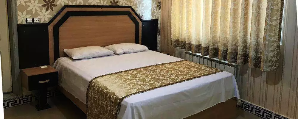 اتاق هتل بهمن با تخت دونفره و روتختی طرح‌دار