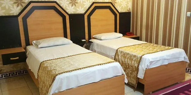 دو تخت یک‌نفره با روتختی طلایی در هتل بهمن