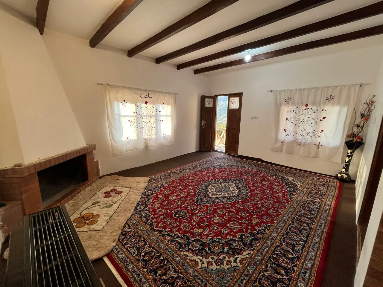 اتاق بزرگ با فرش ایرانی و شومینه اقامتگاه نماشان