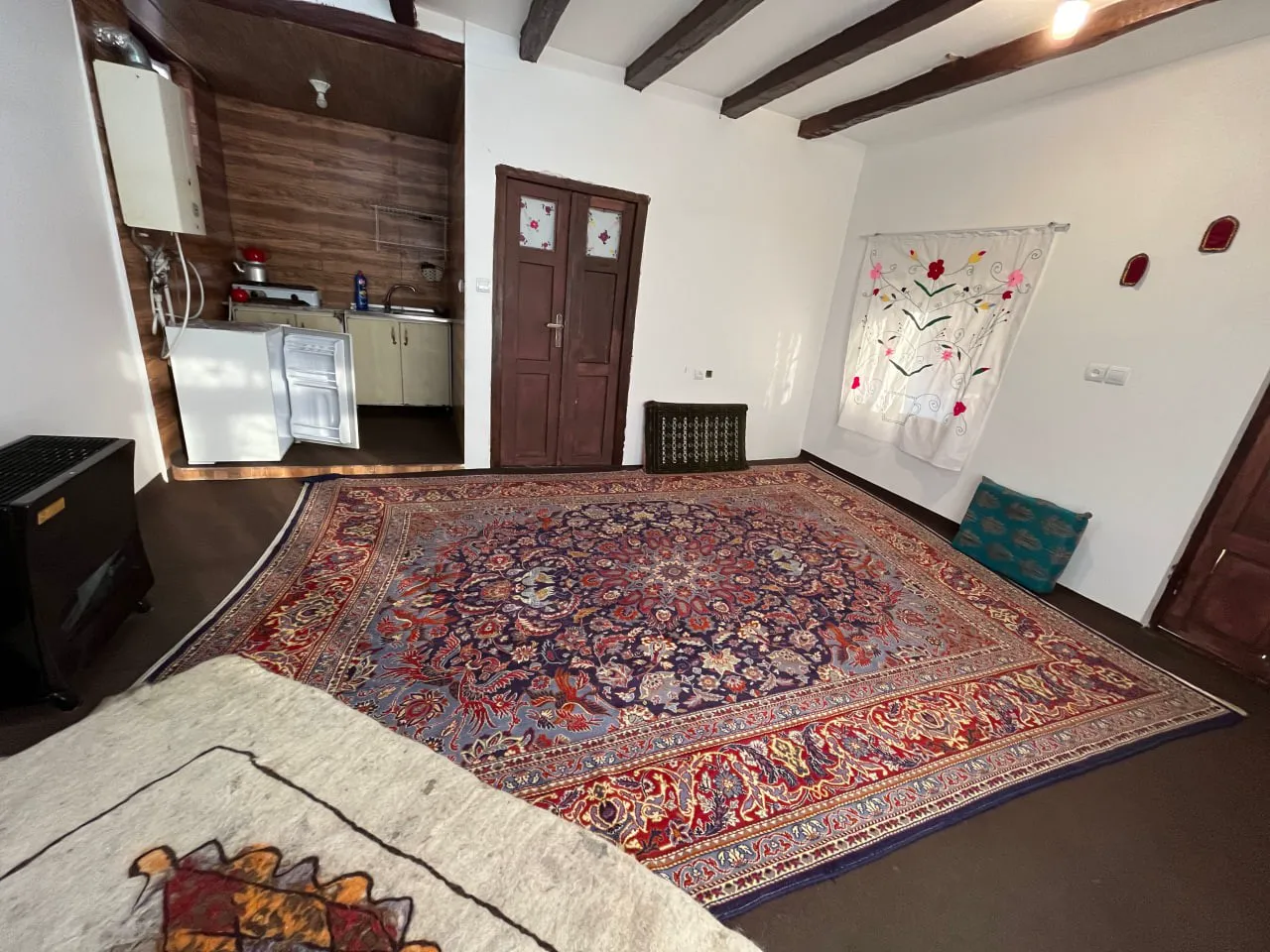 فضای نشیمن اقامتگاه نماشان با فرش دستباف و آشپزخانه