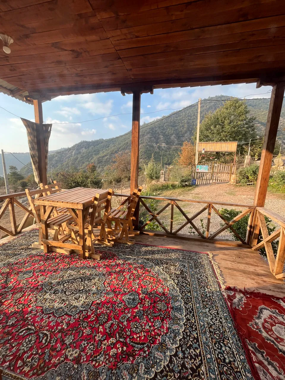 تراس چوبی با فرش و چشمانداز کوهستان اقامتگاه نماشان