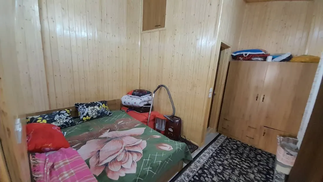 اتاق خواب چوبی با تخت گل‌دار باغ ملک