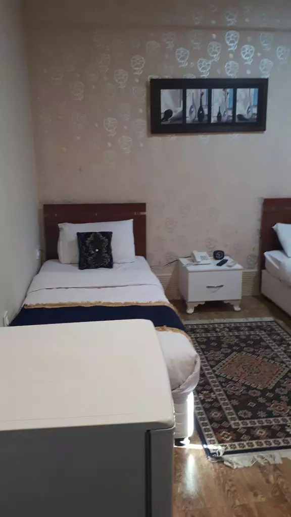 دو تخت یکنفره و میز کنار تخت در اتاق هتل آکراس
