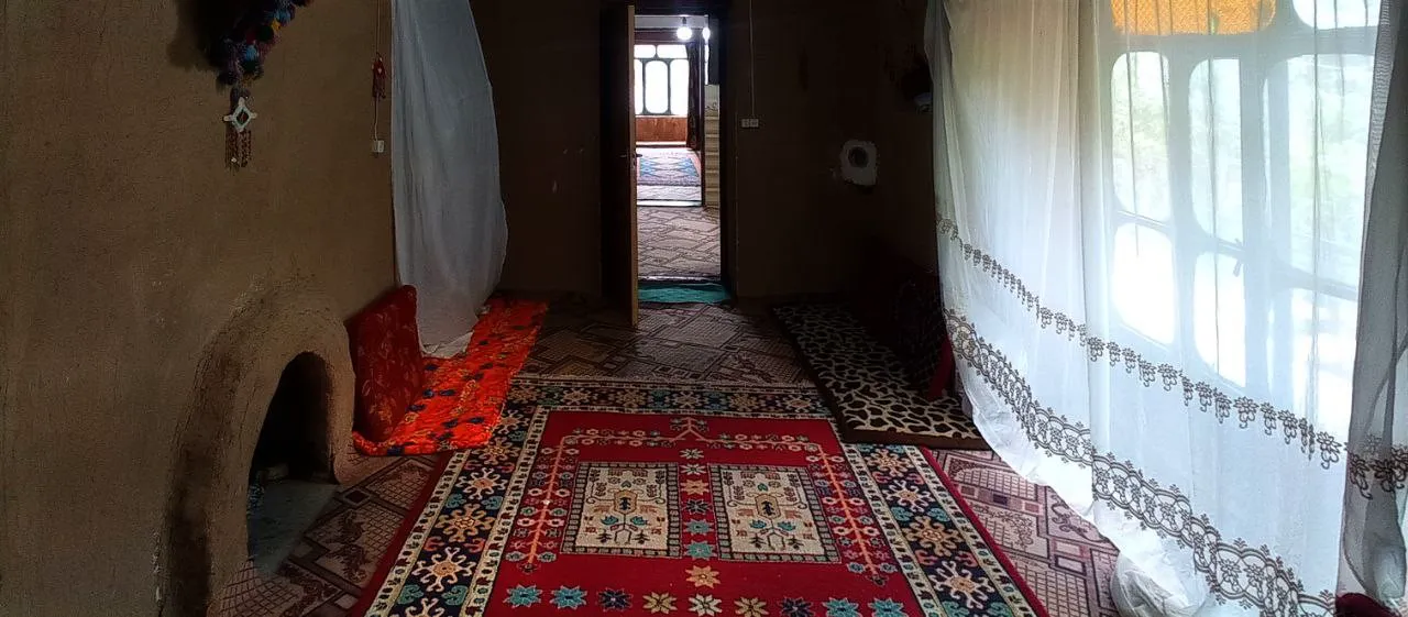 اتاق شاه رستم با فرش‌های رنگارنگ و پنجره پرده‌دار
