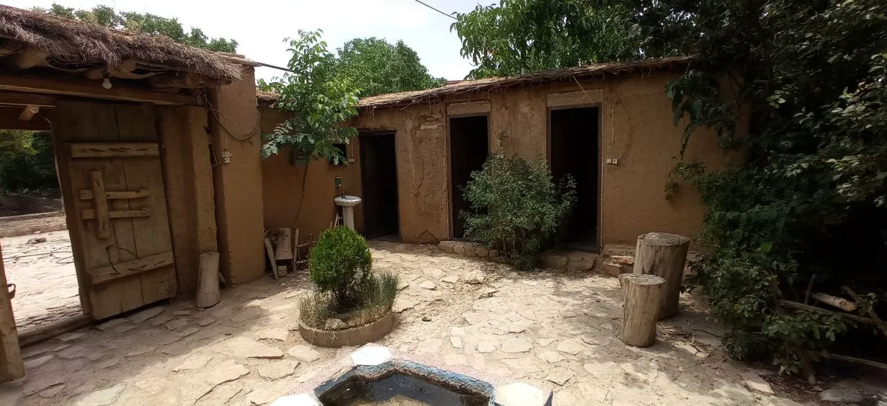 حیاط سنگ‌فرش اقامتگاه شاه رستم با خانه‌های کاهگلی