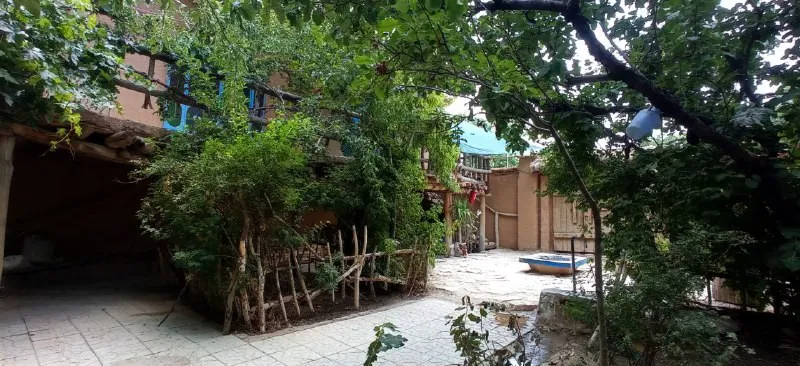 حیاط درخت‌کاری‌شده اقامتگاه شاه رستم با قایق کوچک