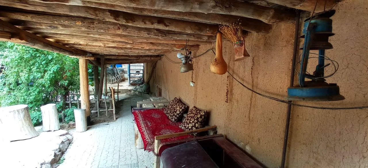 نشیمن سنتی شاه رستم با فرش قرمز و تیرهای چوبی