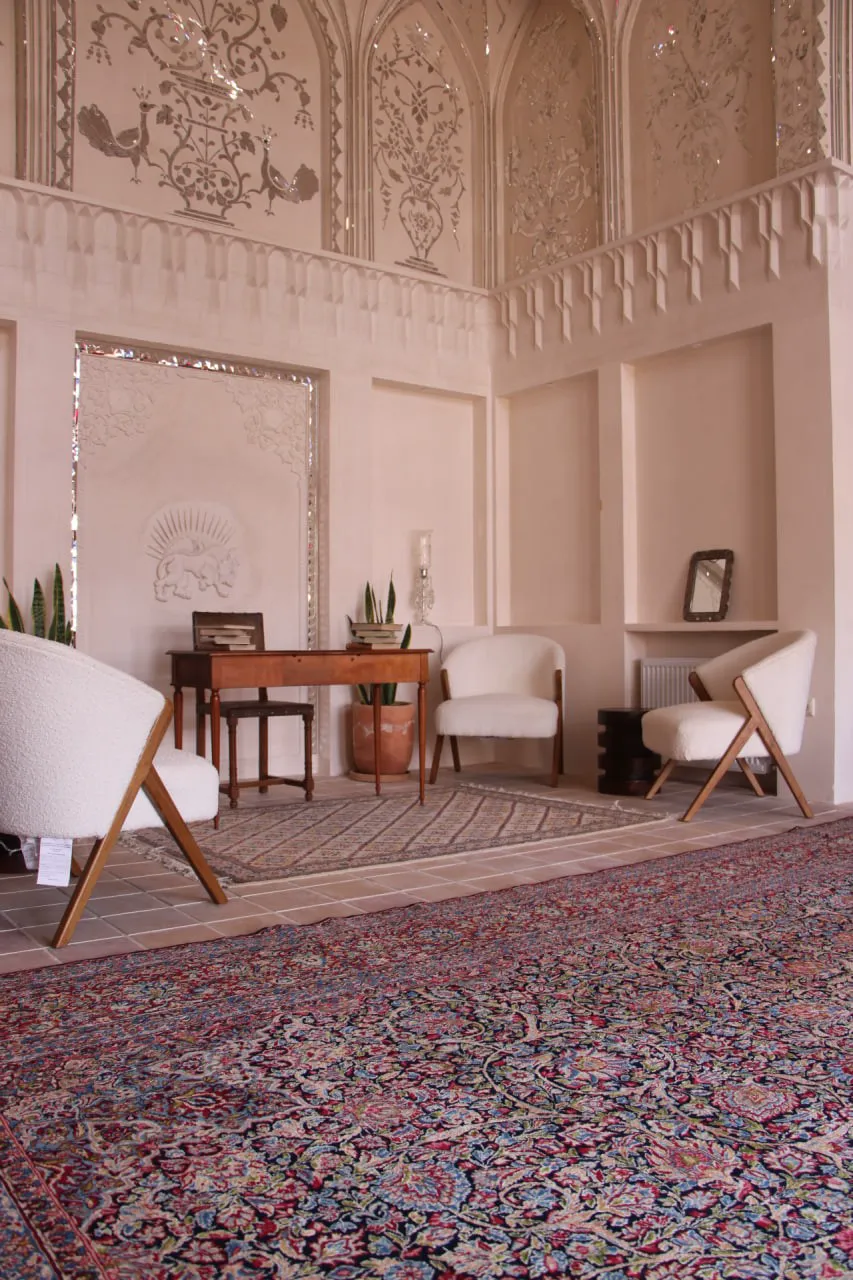 فضای نشیمن عمارت بالابان با فرش دست‌باف و گچ‌بری