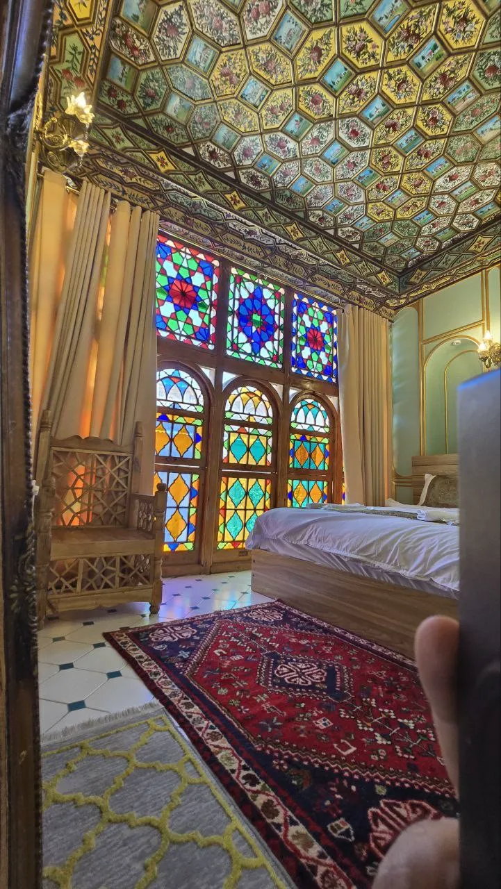 اتاق عمارت جهانشاهی با پنجرههای رنگی و فرش قرمز