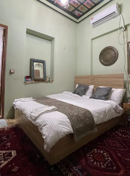 اتاق خواب عمارت جهانشاهی با تخت چوبی و فرش ایرانی