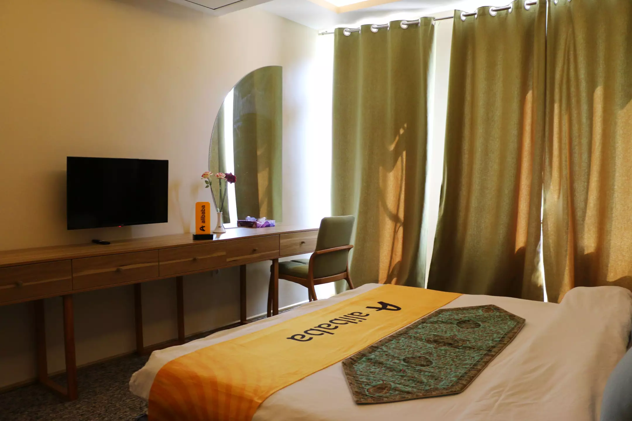 تخت اتاق با روتختی نارنجی و میز تلویزیون، هتل کوت