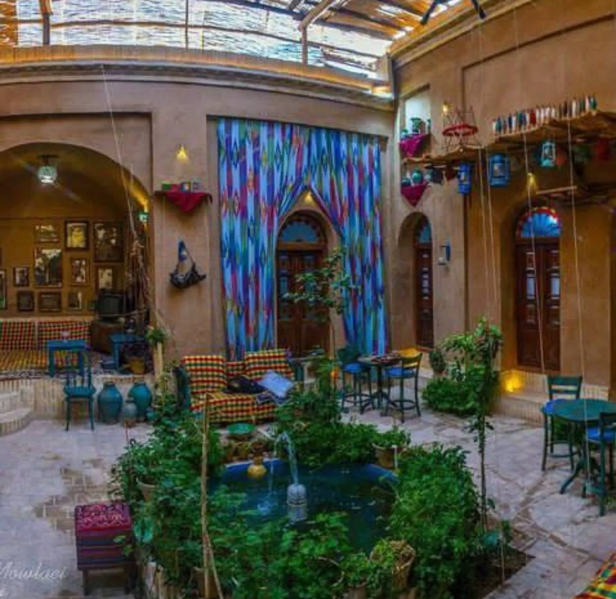 حیاط هتل هشت با حوض، گیاهان و میزهای نشیمن