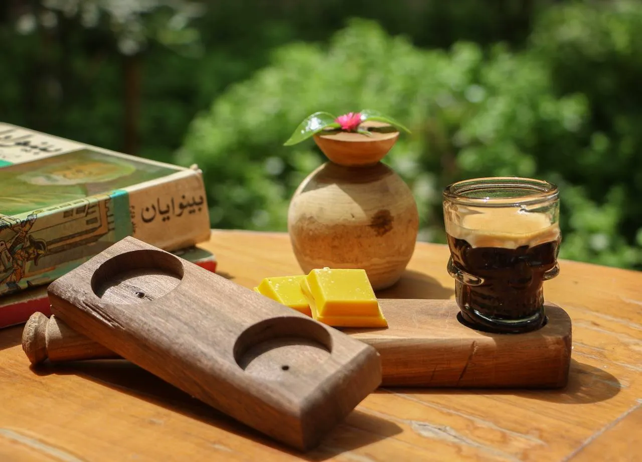 چای و شیرینی روی میز چوبی در فضای سبز هتل هشت