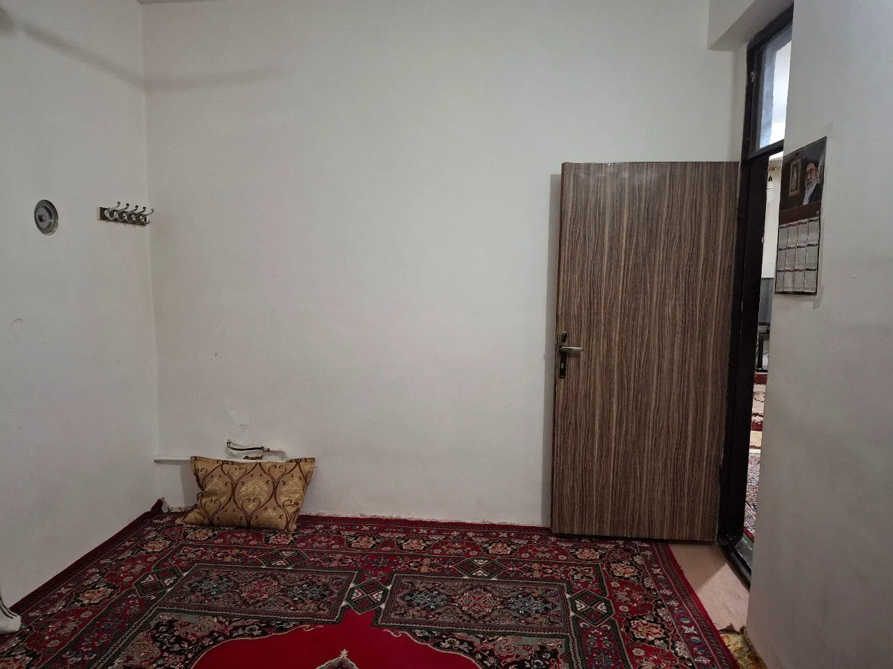 اتاق عمو رضا با فرش قرمز و در چوبی