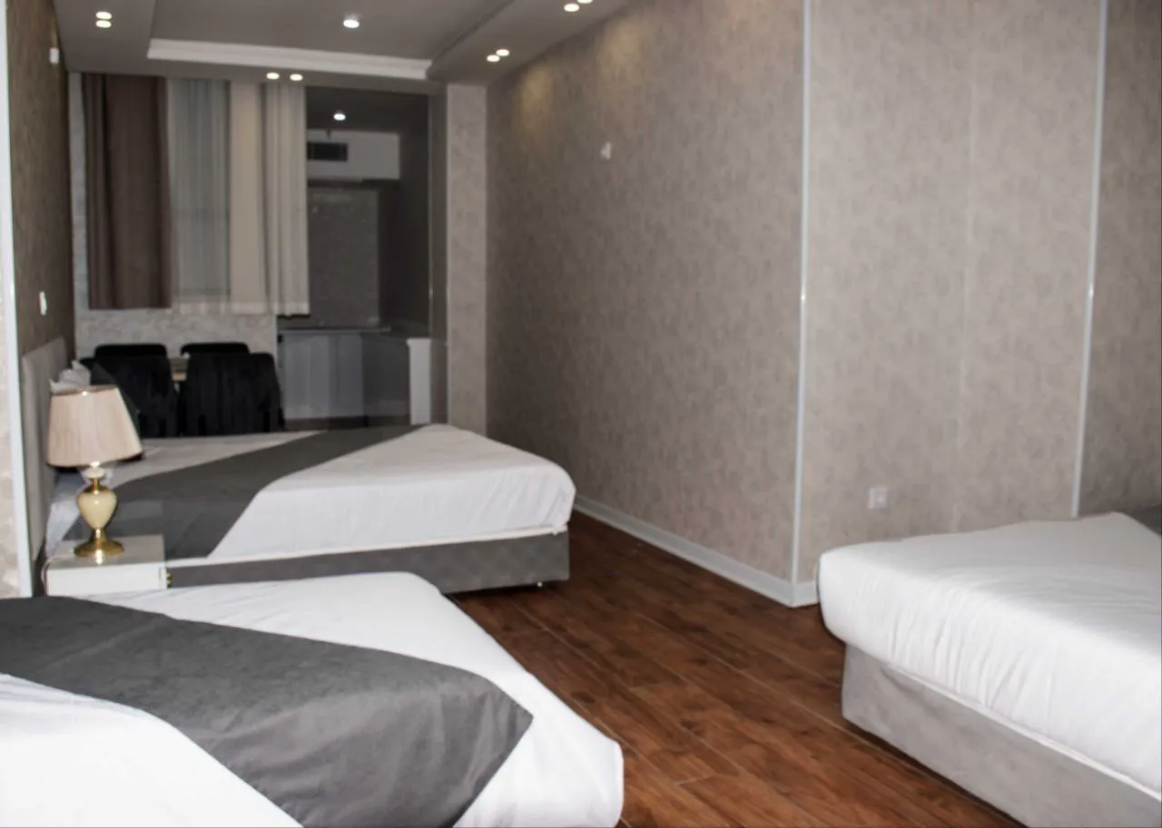 اتاق هتل پارسی با سه تخت و کف‌پوش چوبی
