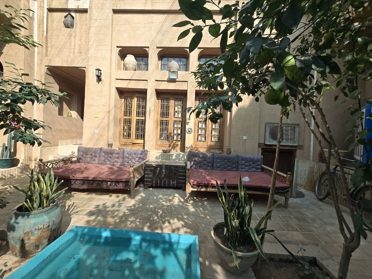 حیاط هتل شهداد با حوض و تختهای سنتی