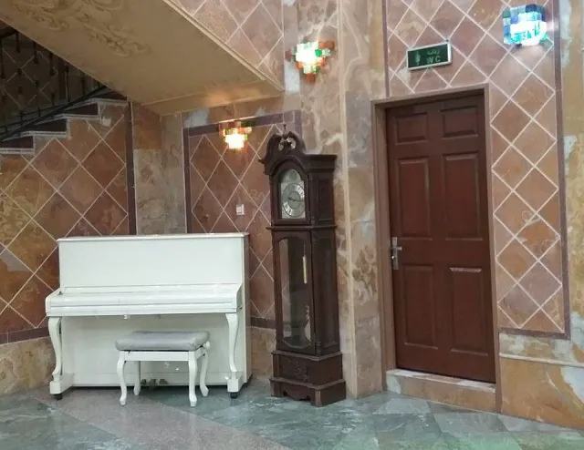 پیانوی سفید و ساعت ایستاده در لابی هتل نوید