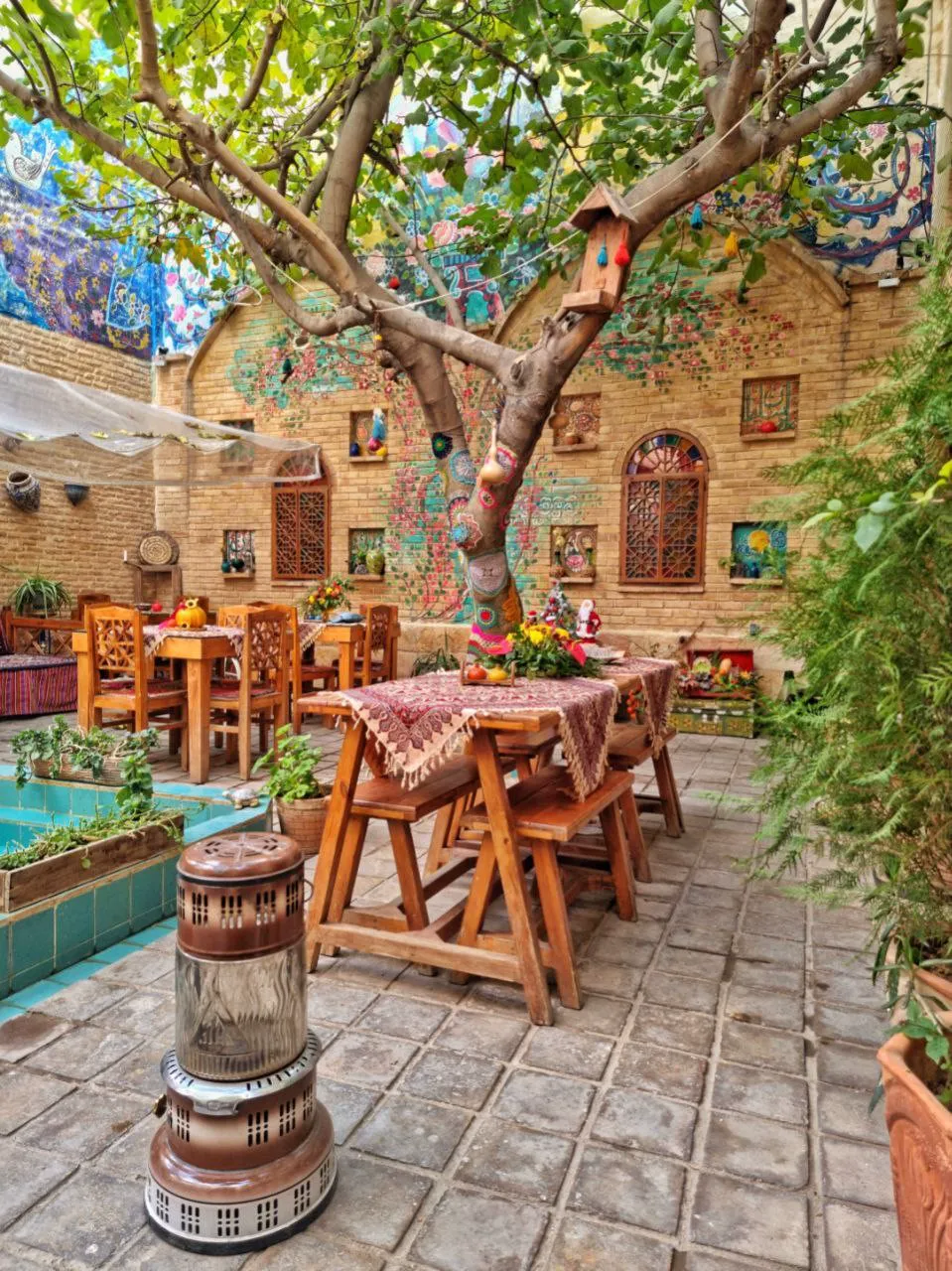 میزهای چوبی زیر درخت در حیاط ماه سلطان