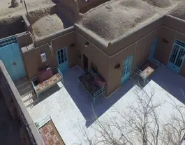 نمای هوایی حیاط خانه خشتی با تخت‌های سنتی