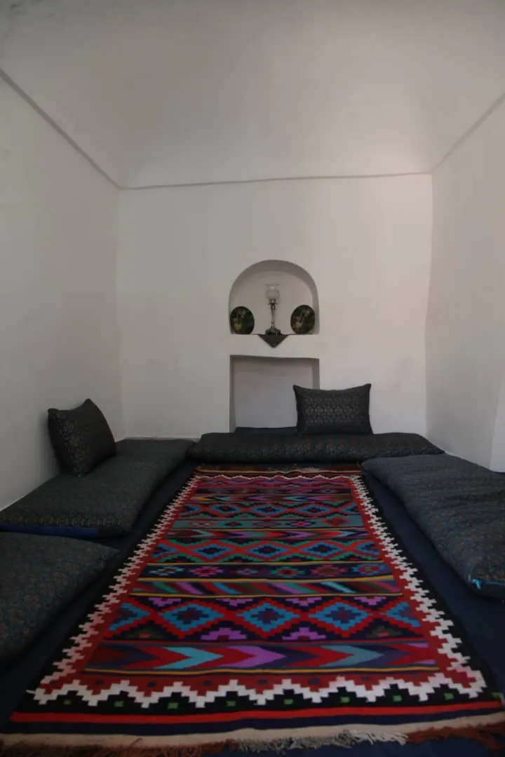 اتاق نشیمن سنتی خانه خشتی با فرش دست‌باف