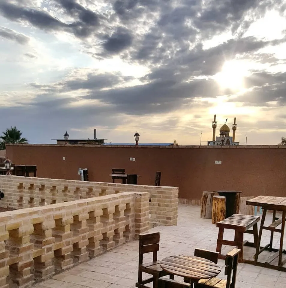 تراس خانه خشتی با میز و صندلی زیر آسمان ابری