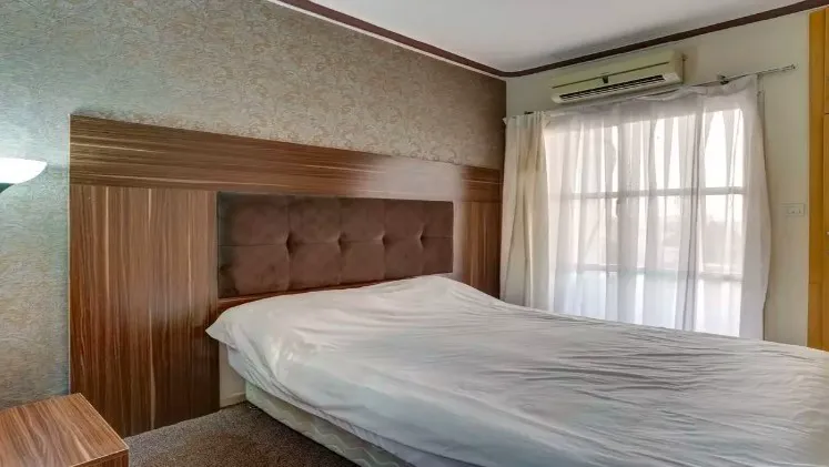 اتاق خواب هتل شمس با تخت دونفره و پنجره پردهدار