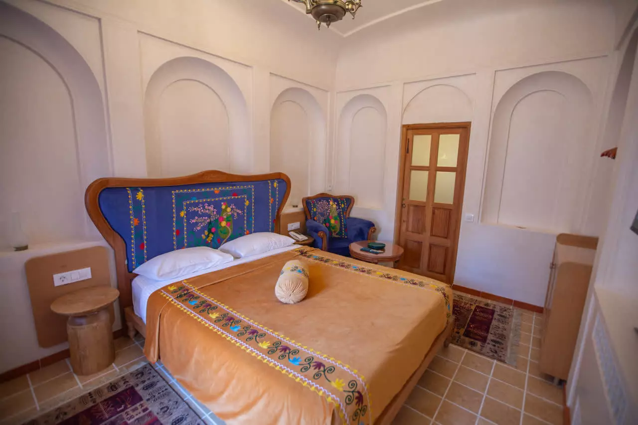 اتاق عمارت آقاحسینی با تخت و پشتیهای گلدوزیشده