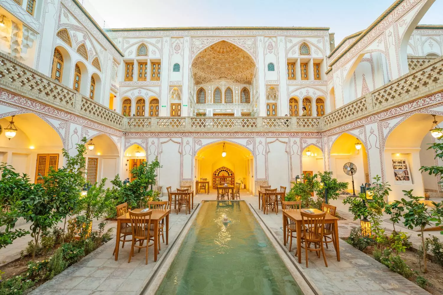 حیاط عمارت آقاحسینی با حوض مرکزی و میزهای چوبی