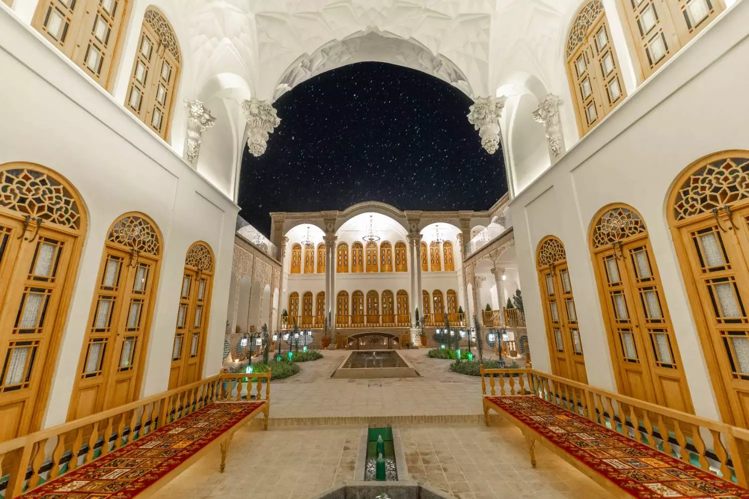 راهروی عمارت آقاحسینی با نیمکت‌های سنتی در شب